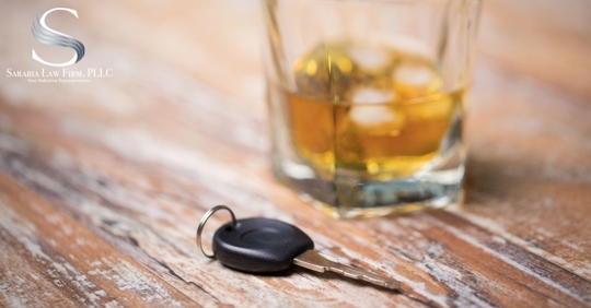 car keys on a table with a glass of alcohol
